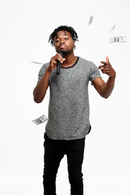 Jeune homme africain chantant au microphone sur blanc.