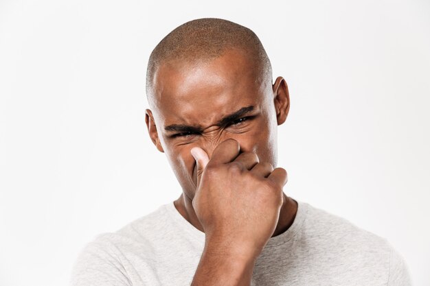 Jeune homme africain ferme un nez d'une puanteur.