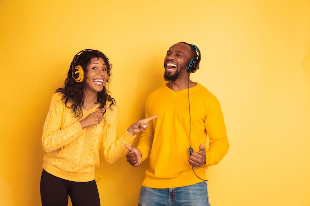 Jeune homme afro-américain émotionnel et femme dans des vêtements décontractés lumineux sur l'espace jaune