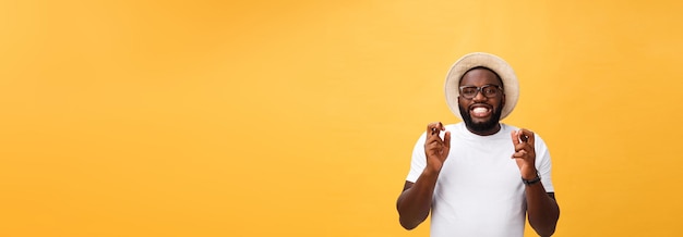 Photo gratuite jeune homme afro-américain sur fond isolé souriant croisant les doigts avec espoir et yeux fermés