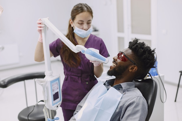 Jeune homme afro-américain. Guy visitant le cabinet du dentiste pour la prévention de la cavité buccale. Homme et médecin de famille pendant le contrôle des dents.