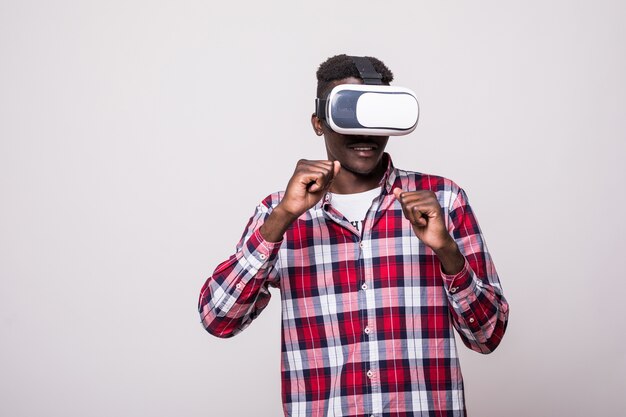 Jeune homme afro-américain heureux et excité portant des lunettes de réalité virtuelle vr bénéficiant d'un jeu vidéo isolé dans l'innovation et la boîte de jeu