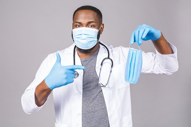 Jeune homme afro-américain noir dans le domaine médical, portant un manteau blanc et un masque facial, offrant un masque facial
