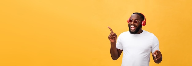 Photo gratuite jeune homme afro-américain portant un casque et profiter de la musique sur fond d'or jaune