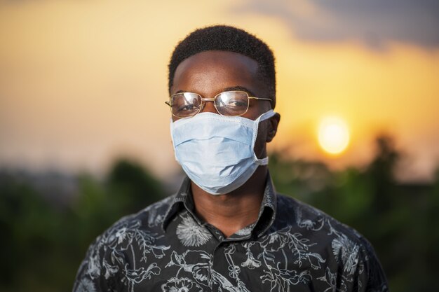 Jeune homme afro-américain portant un masque protecteur posant à l'extérieur