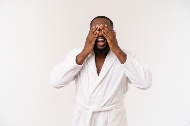 Jeune homme afro-américain portant un peignoir sur fond blanc isolé pensant avoir l'air fatigué et ennuyé par des problèmes de dépression