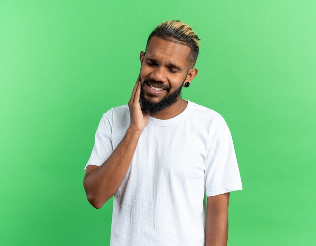 Jeune homme afro-américain en t-shirt blanc à la confusion avec la main sur son visage