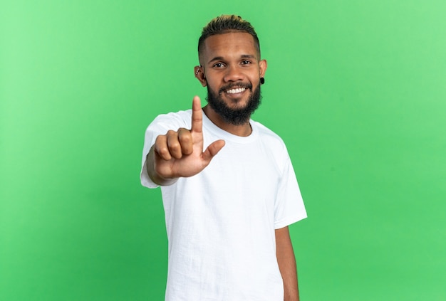 Jeune homme afro-américain en t-shirt blanc regardant la caméra avec un grand sourire