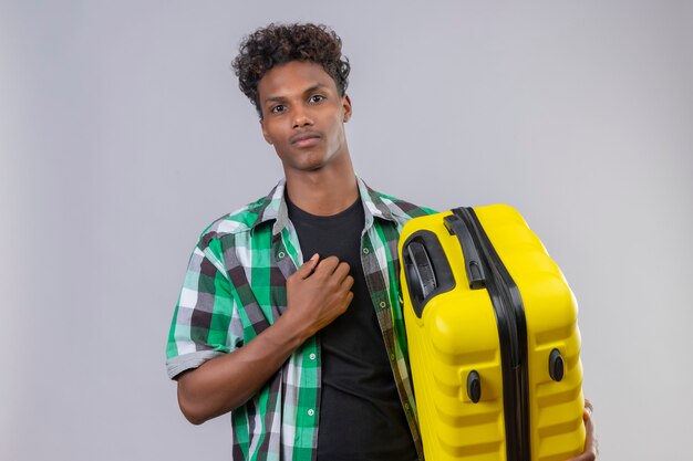 Jeune homme afro-américain voyageur tenant valise avec visage sérieux