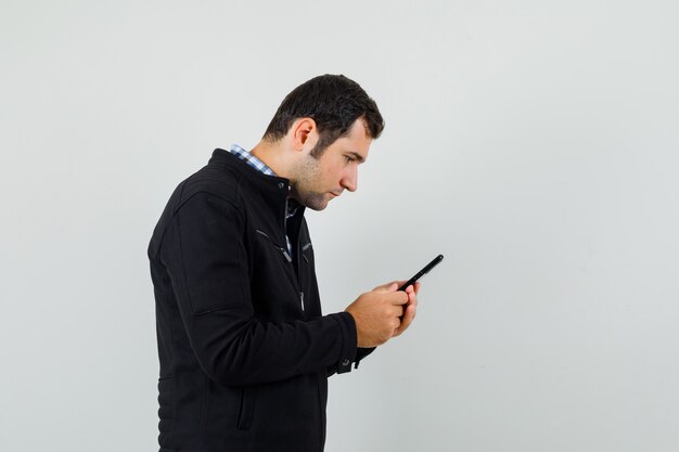 Jeune homme à l'aide de téléphone portable en chemise, veste et à la recherche de occupé.