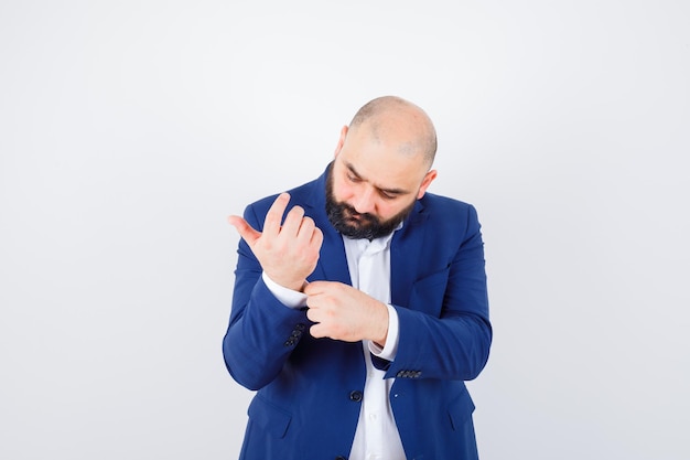 Jeune homme ajustant la manche de sa chemise en chemise blanche, veste et élégant. vue de face.