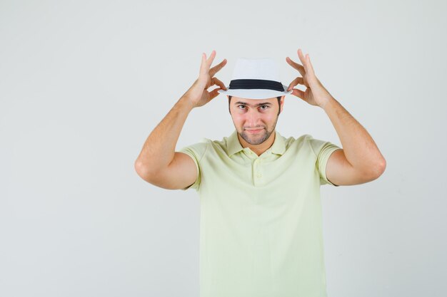 Jeune homme ajustant son chapeau en t-shirt et à la confiance