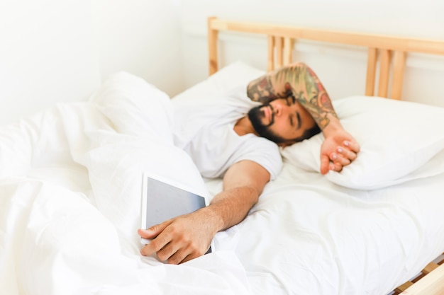 Jeune homme allongé sur le lit avec tablette numérique