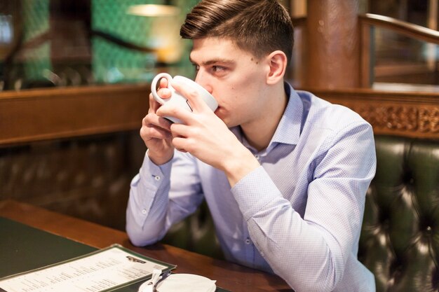 Jeune homme, apprécier, boisson chaude, dans, restaurant