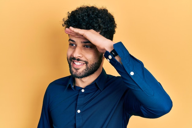 Jeune homme arabe avec barbe portant une chemise décontractée très heureux et souriant regardant loin avec la main sur la tête. notion de recherche.