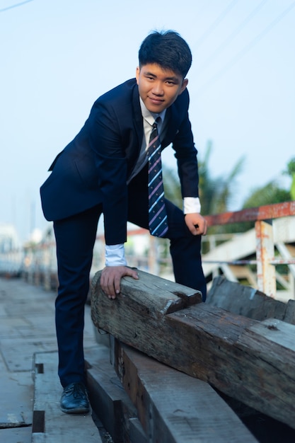 Jeune homme asiatique en costume accroupi sur une pile de journaux