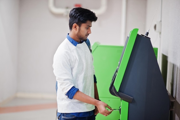 Un jeune homme asiatique a mis sa carte de crédit pour retirer de l'argent d'un guichet automatique vert