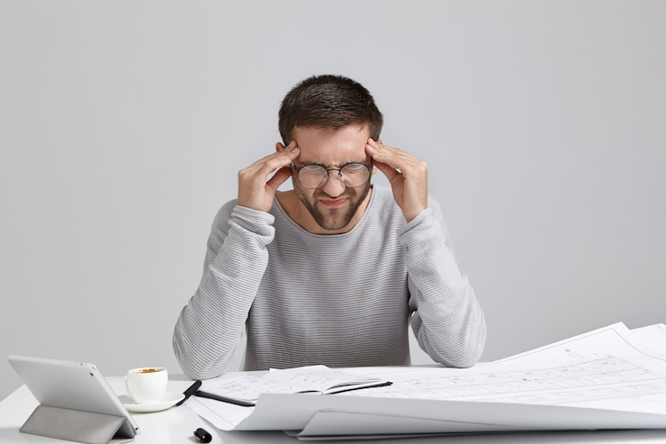 Photo gratuit jeune homme assis au bureau et faire de la paperasse