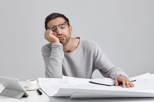 Jeune homme assis au bureau et faire de la paperasse