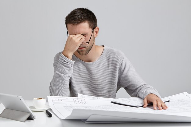 Jeune homme assis au bureau et faire de la paperasse