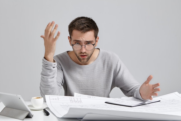 Jeune homme assis au bureau et faire de la paperasse