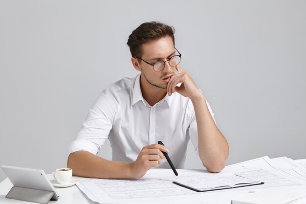 Jeune homme assis au bureau et faire de la paperasse