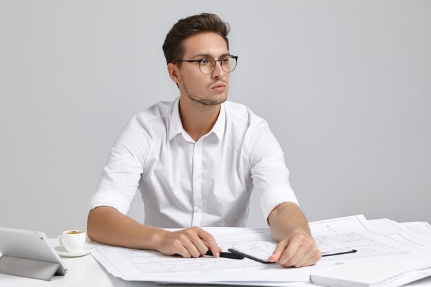 Jeune homme assis au bureau et faire de la paperasse