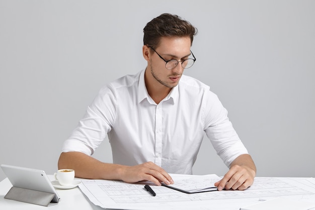 Jeune homme assis au bureau et faire de la paperasse