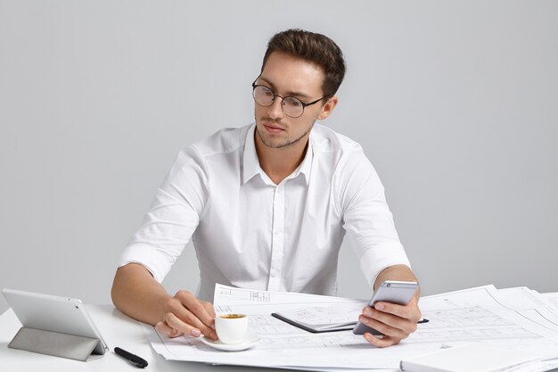 Jeune homme assis au bureau et faire de la paperasse