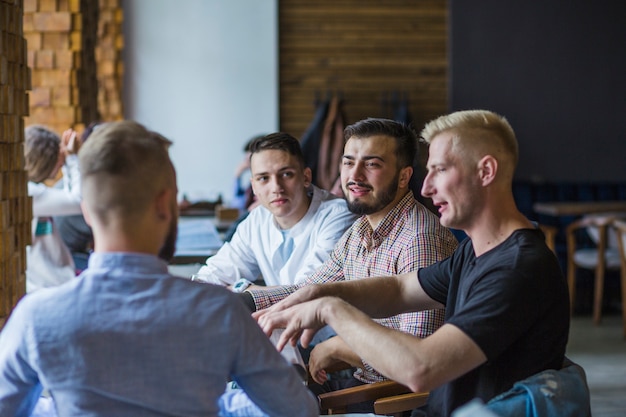 Photo gratuite jeune homme assis dans un restaurant expliquant la stratégie à ses amis