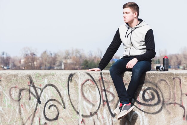 Jeune homme assis sur un mur de graffitis
