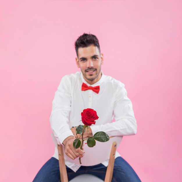 Jeune homme assis avec une rose sur une chaise