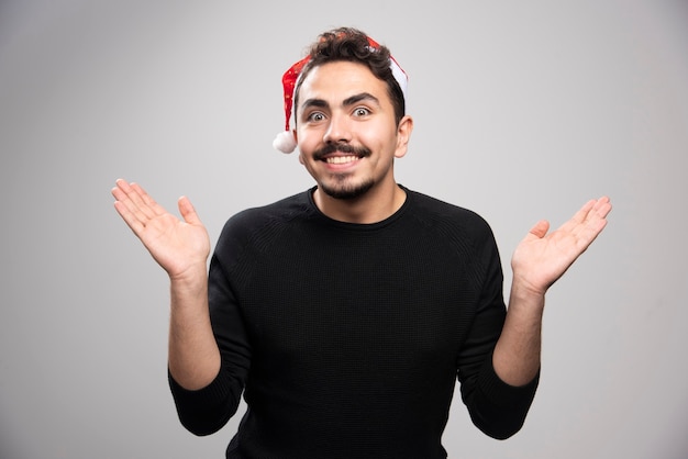 Jeune homme au chapeau du père Noël tenant quelque chose d'invisible dans ses mains.