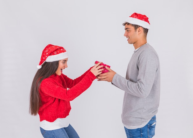 Jeune homme au chapeau de Noël avec boîte près de femme surprise