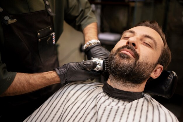 Jeune homme au salon de coiffure se faisant tailler la barbe