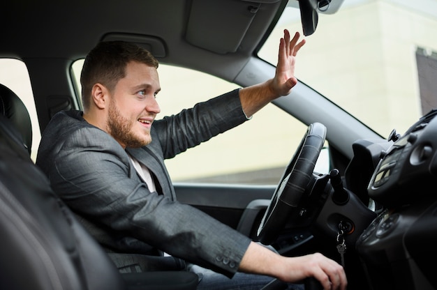 Jeune homme au volant salue quelqu'un