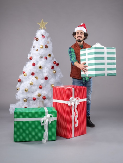 Photo gratuite jeune homme autour de cadeaux de noël sur fond gris