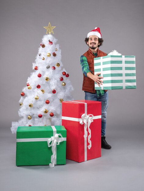 jeune homme autour de cadeaux de Noël sur fond gris