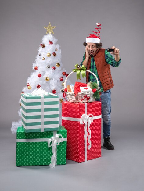 jeune homme autour de cadeaux de Noël sur fond gris