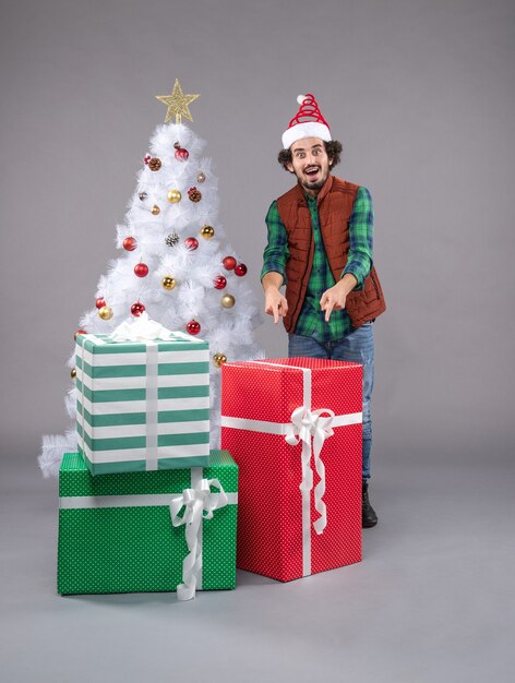 jeune homme autour de cadeaux de Noël sur fond gris