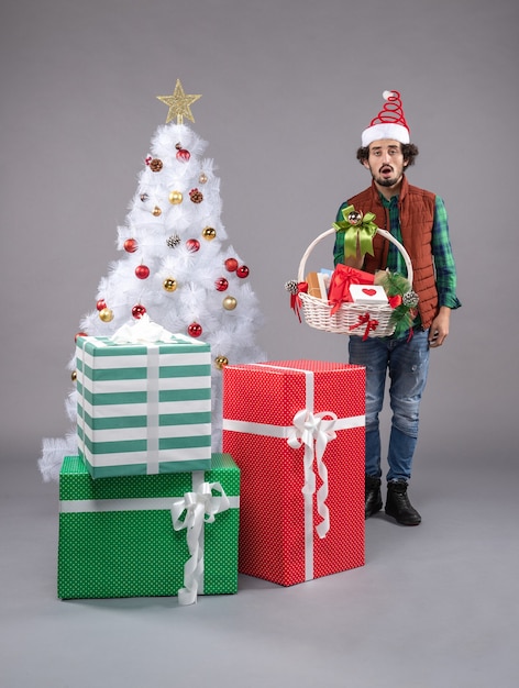 jeune homme autour de cadeaux de Noël sur fond gris
