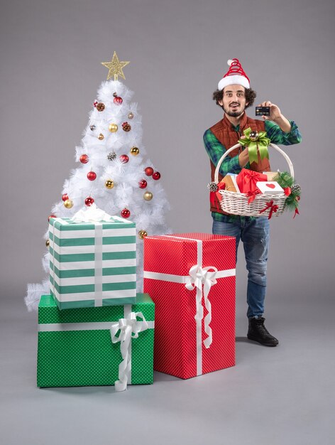 jeune homme autour des cadeaux de vacances sur gris