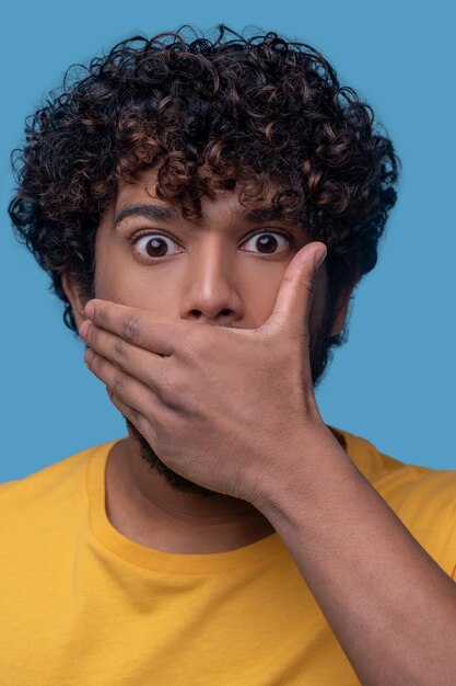 Jeune homme aux cheveux noirs avec une expression choquée