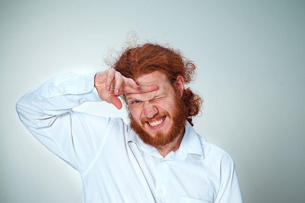 Le jeune homme aux longs cheveux roux regardant la caméra, vissant ses yeux