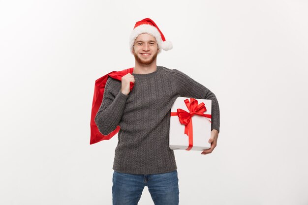 Jeune homme barbe heureux tenant le sac de santa et cadeau blanc.