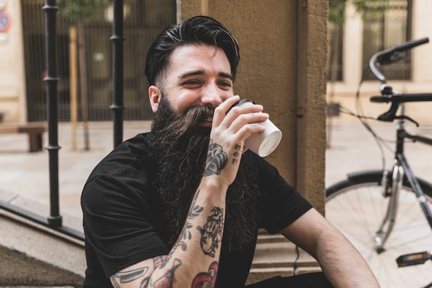 Photo gratuite jeune homme barbu buvant le café à emporter