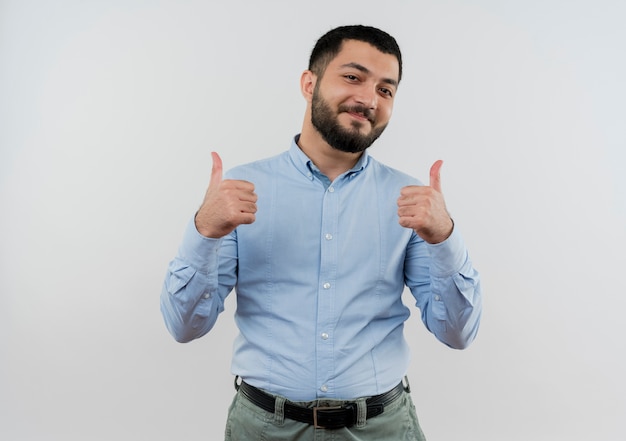 Jeune homme barbu en chemise bleue souriant montrant les pouces vers le haut