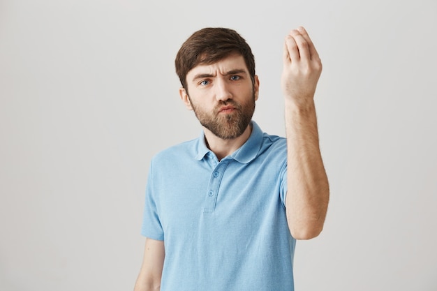 Jeune homme barbu dérangé et ennuyé posant