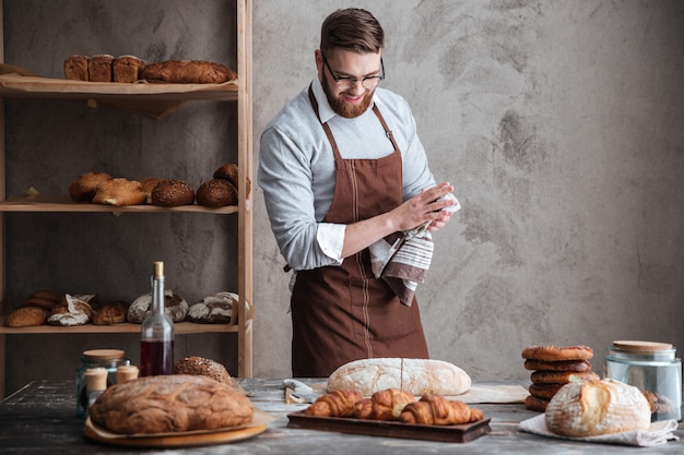 Jeune homme barbu gai portant des lunettes boulanger