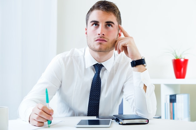 Photo gratuite jeune homme beau travaillant dans son bureau.